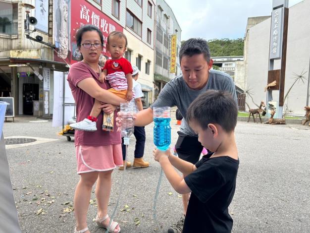 家長與小朋友一人拿著一個的水瓶，觀看水流動的方向